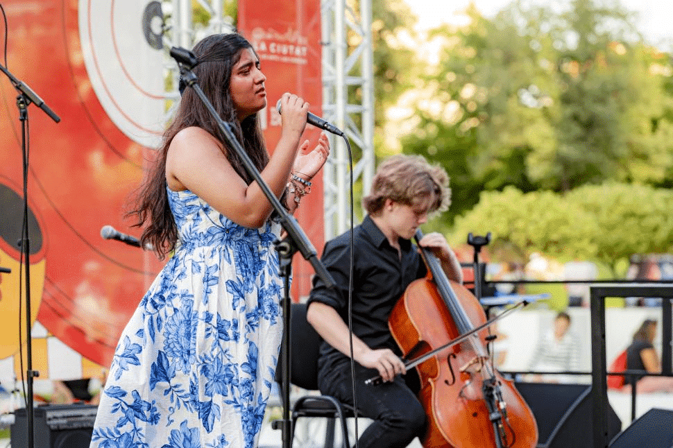 girl sining at a concert supported by a string-instrument player